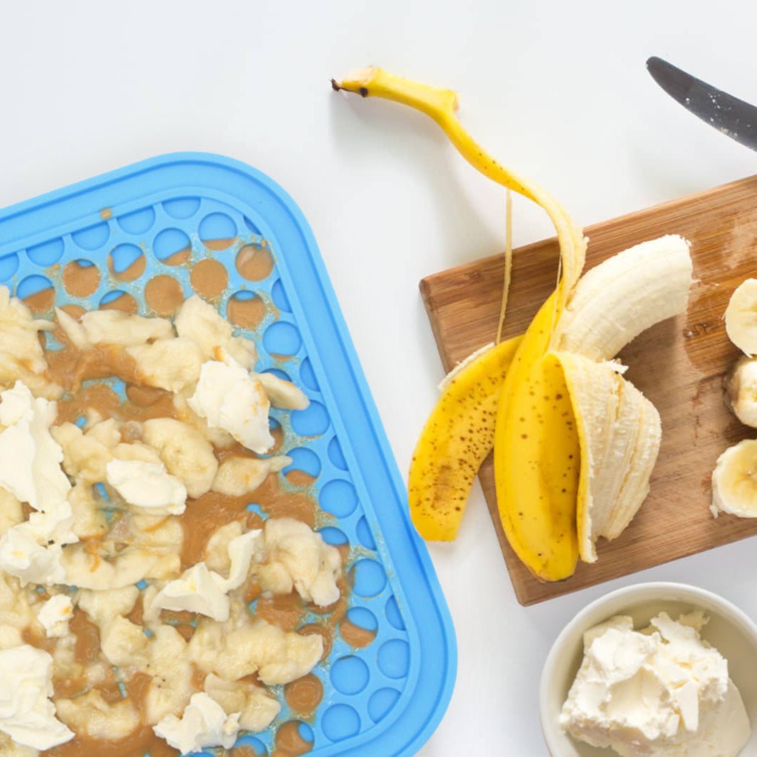 Banana being peeled and sliced on a cutting board with a knife, surrounded by ingredients for a snack.
