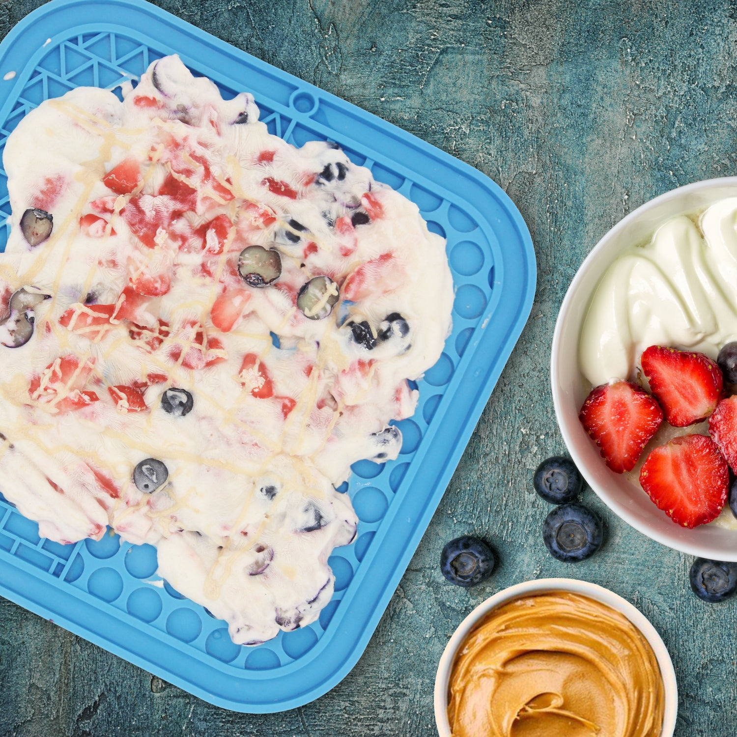Yogurt dessert with berries on a blue tray and in a bowl on a textured blue background