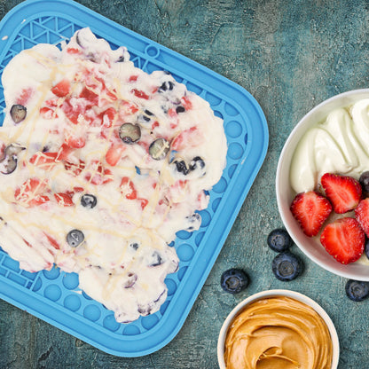 Yogurt dessert with berries on a blue tray and in a bowl on a textured blue background
